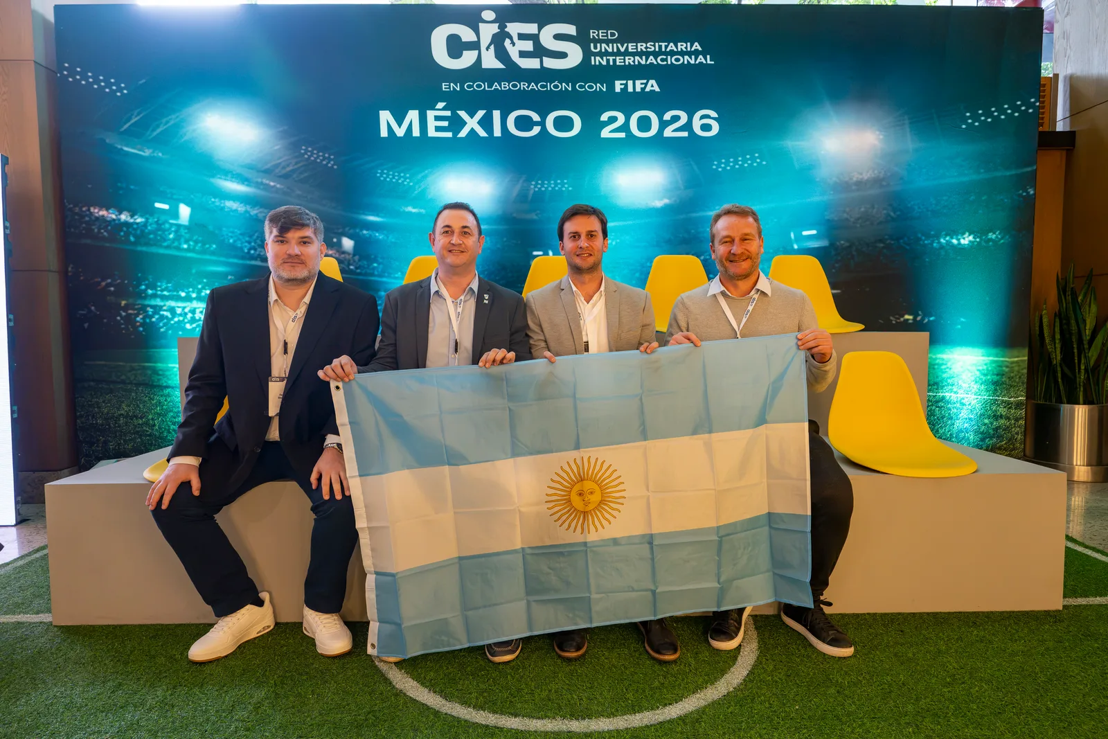 La delegación argentina de la red CIES-UNA con la bandera argentina frente al backdrop oficial de México 2026
